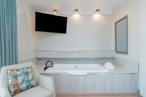 A modern bathroom with a large bathtub, a mounted TV, and a towel rack. - Sandman Suites Vancouver on Davie (Vancouver)