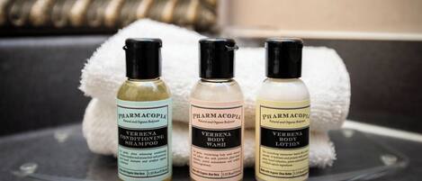 Three bottles of Verbena conditioning shampoo, body wash, and lotion on a tray with a white towel.