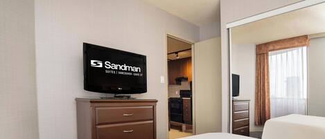 A hotel room with a bed, a TV mounted on the wall, a dresser, and a closet.
