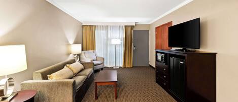 A hotel room with a sofa, a small table, a TV, and a cabinet.