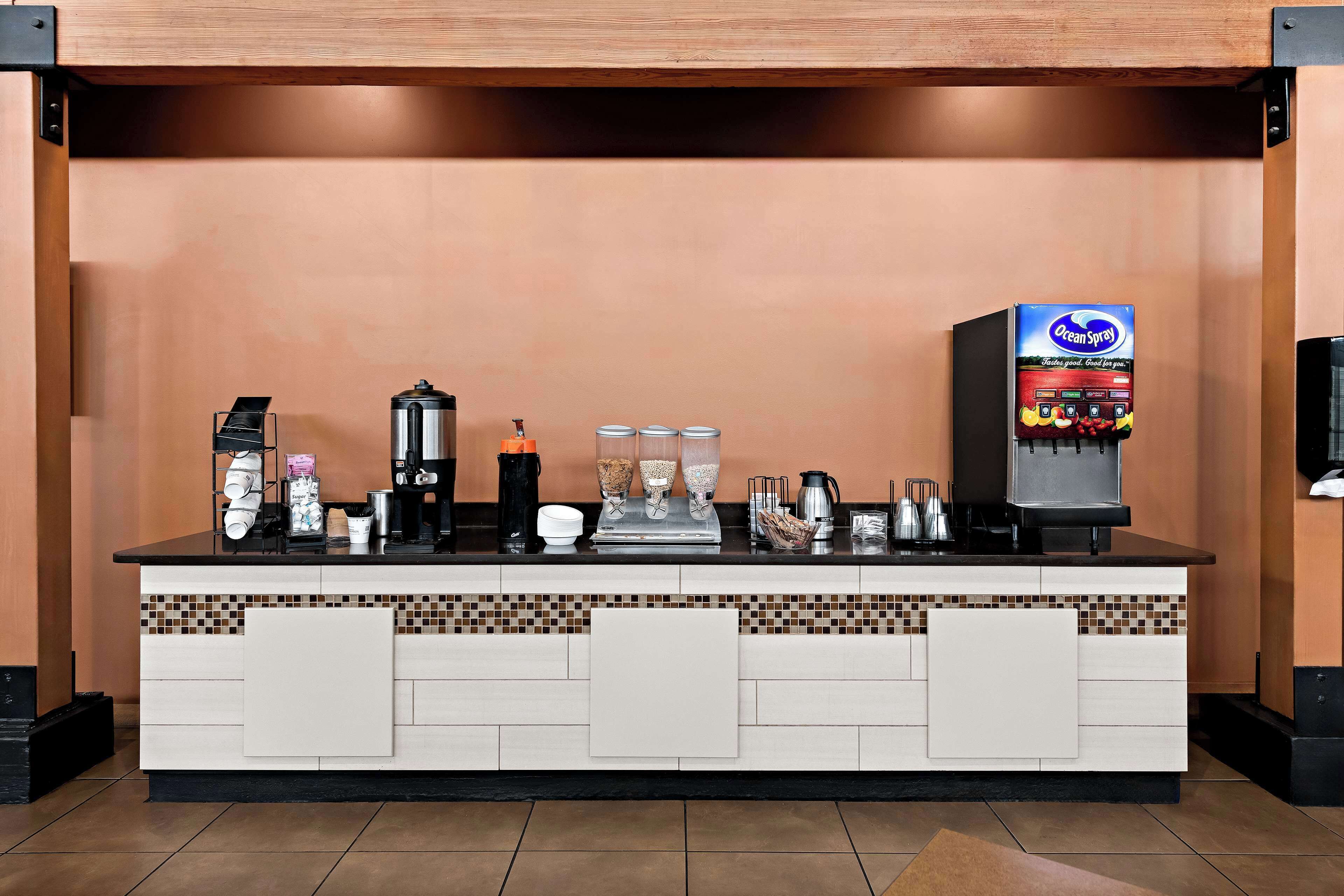A coffee station with a coffee machine, a beverage dispenser, and various coffee-making accessories.