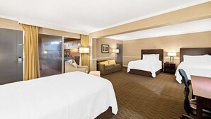 A hotel room with two beds, a sofa, a desk, and a chair.