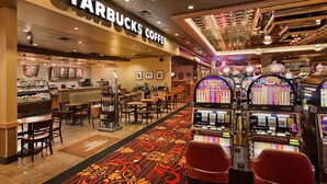 A Starbucks Coffee with a carpeted walkway, tables, chairs, and slot machines. - Maverick Hotel and Casino by Red Lion Hotels (Elko)