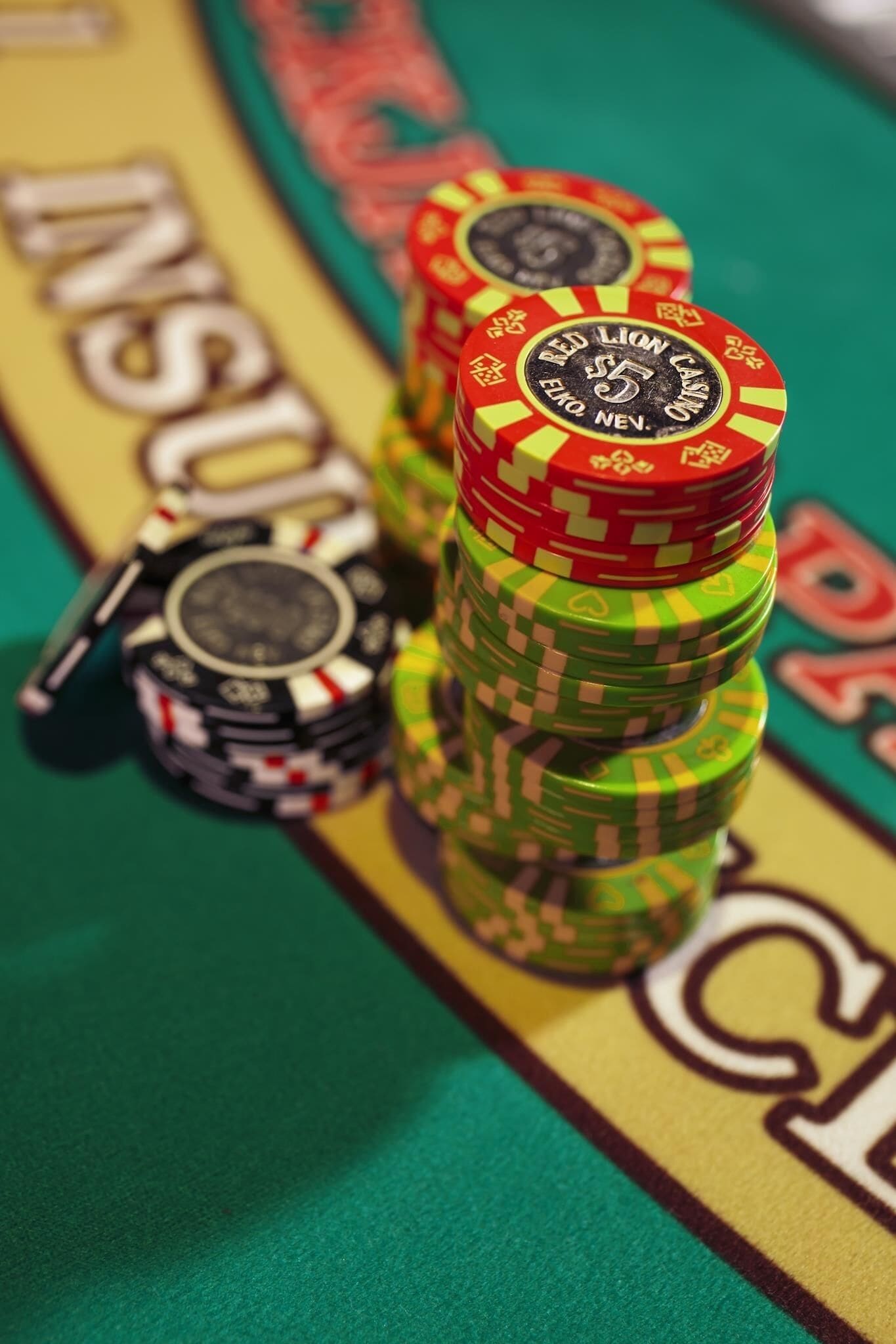Stacks of poker chips on a green tablecloth with the word "INSULT" partially visible.