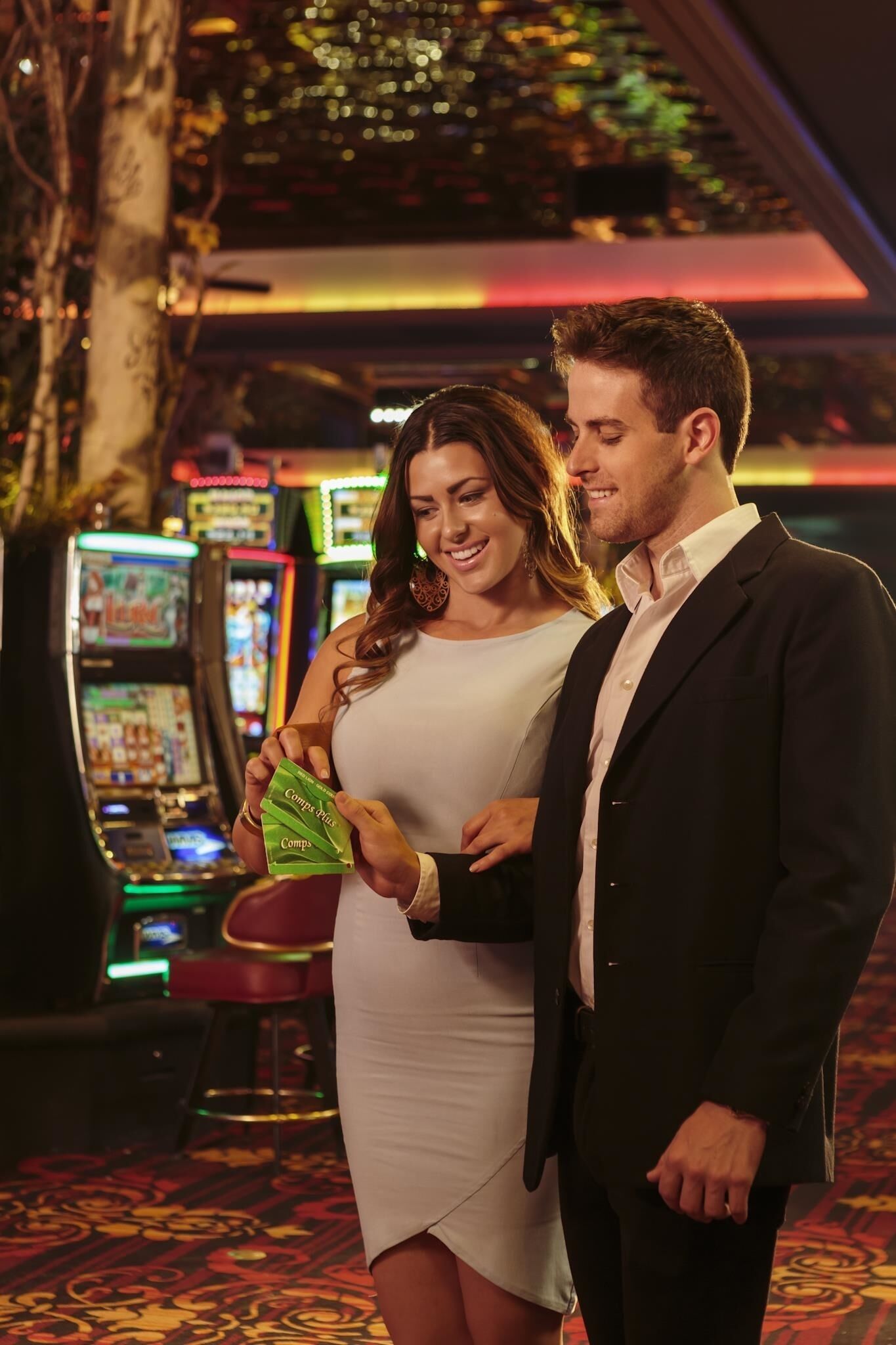 A couple standing in a casino with slot machines in the background.