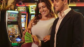 A couple standing in a casino with slot machines in the background.
