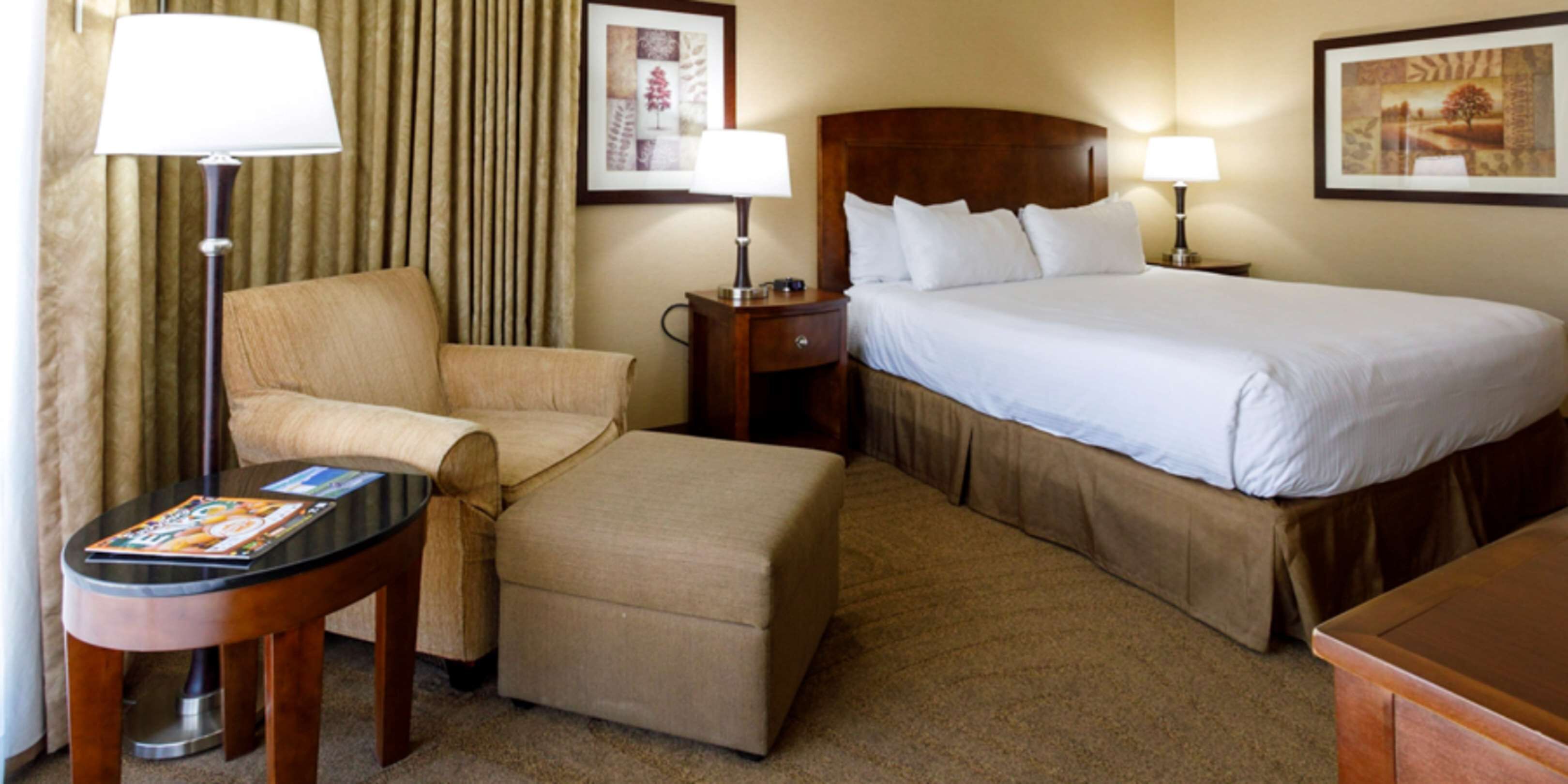Een hotelkamer met een bed, een stoel, een tafel en een lamp.