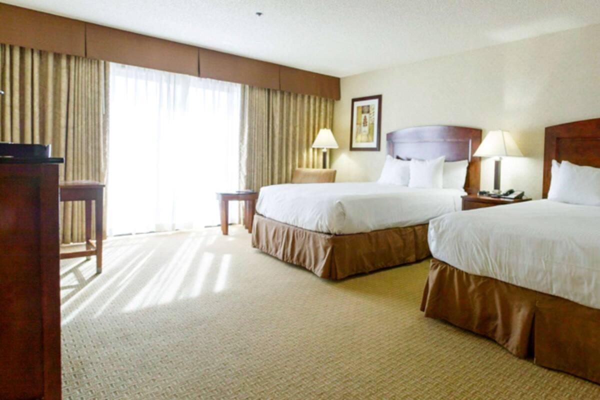 A hotel room with two beds, a desk, and a chair.