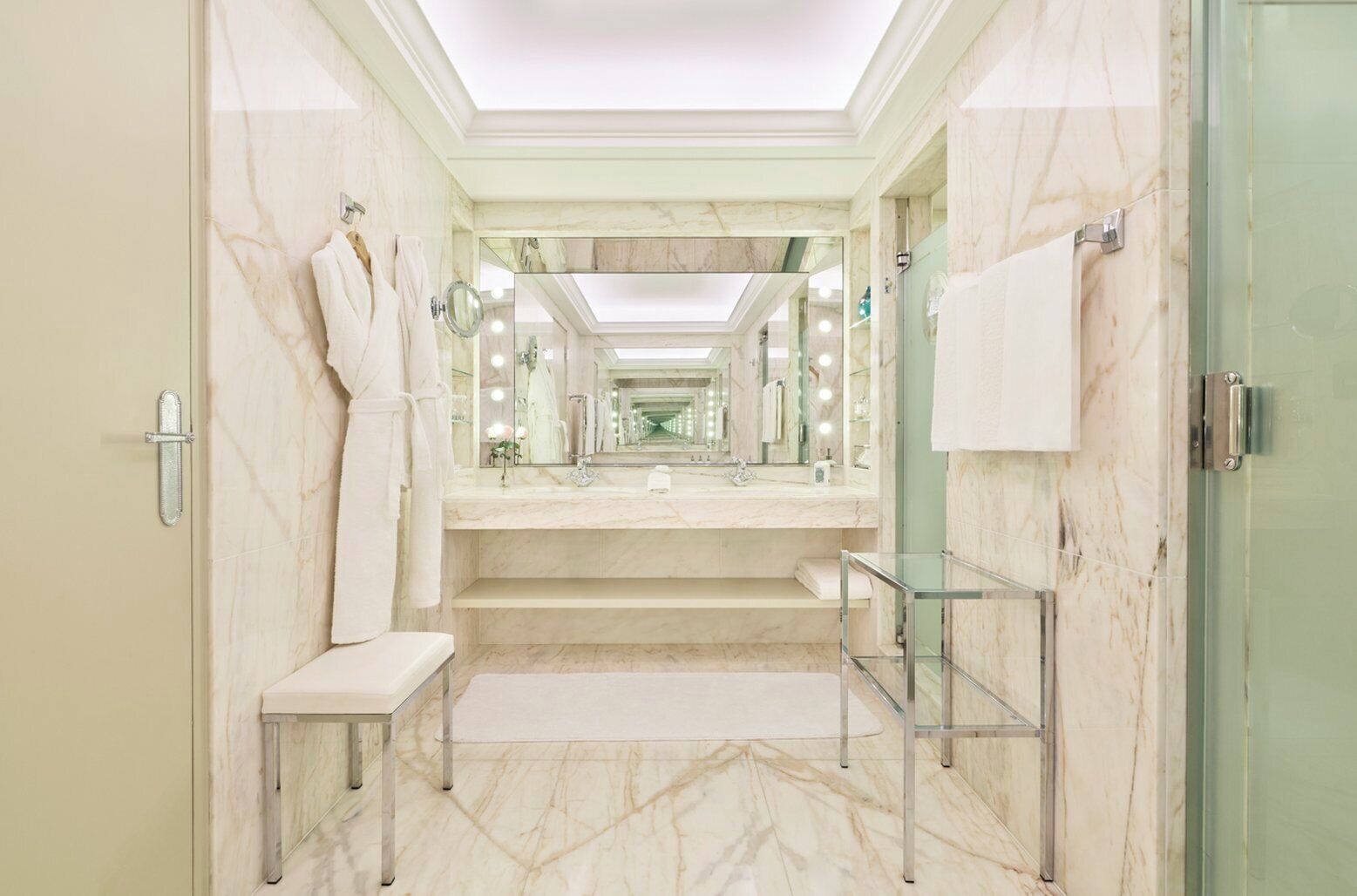 A modern bathroom with marble flooring, a glass shower enclosure, and a vanity with a mirror.