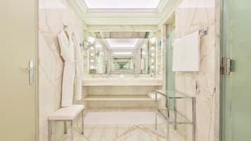 A modern bathroom with marble flooring, a glass shower enclosure, and a vanity with a mirror.