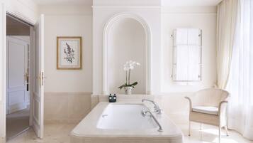 A modern bathroom with a freestanding bathtub, a white sink, and a wicker chair.