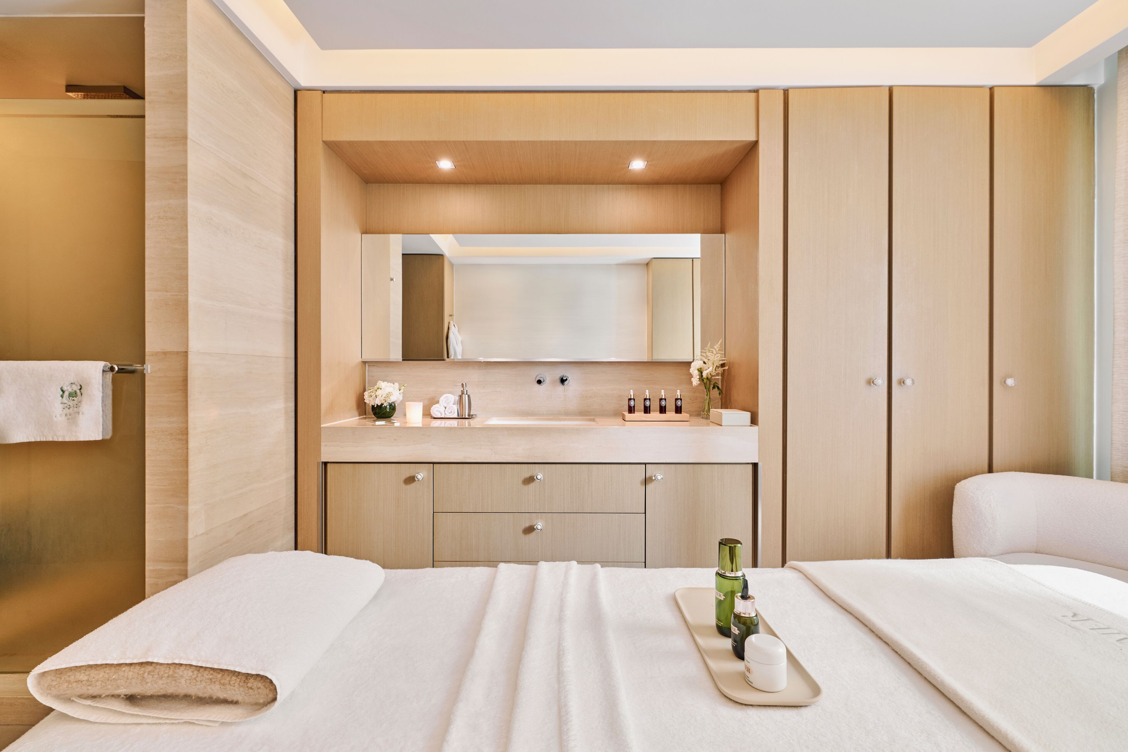 A modern hotel room with a large bed, a bathroom with a shower, and a vanity with a mirror.