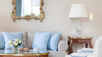 A room with a sofa, a table with a vase of flowers, a lamp, and a mirror with an ornate frame.