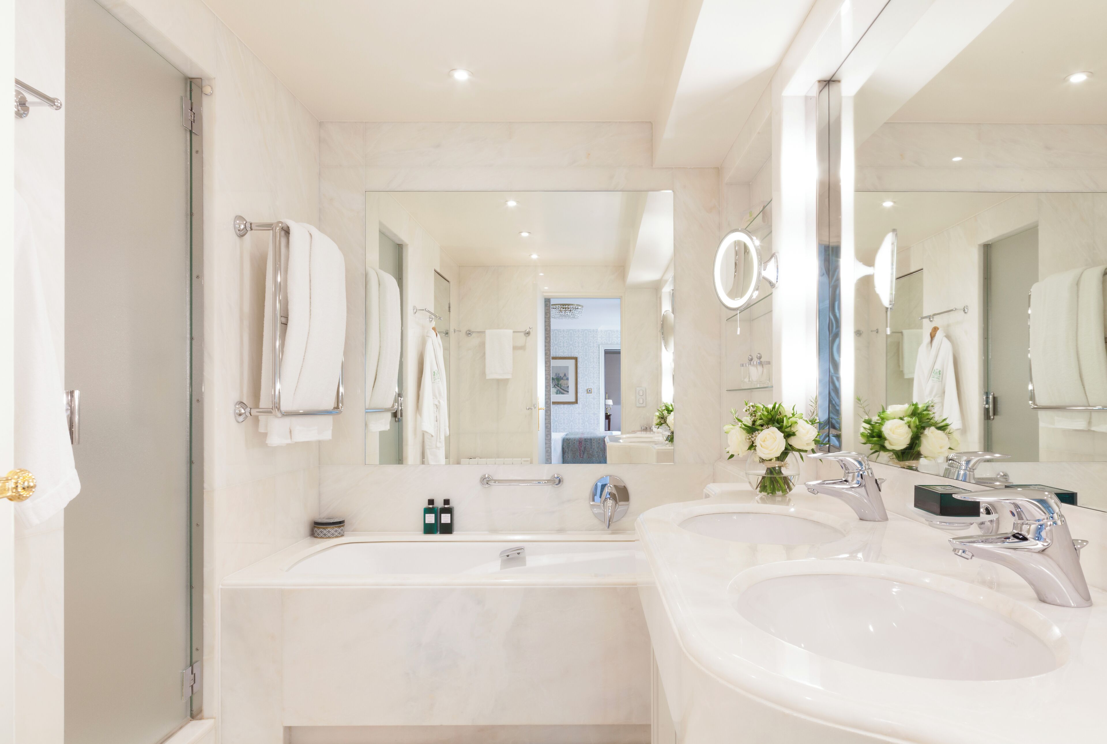 A modern bathroom with two sinks, a large mirror, and a glass shower enclosure.