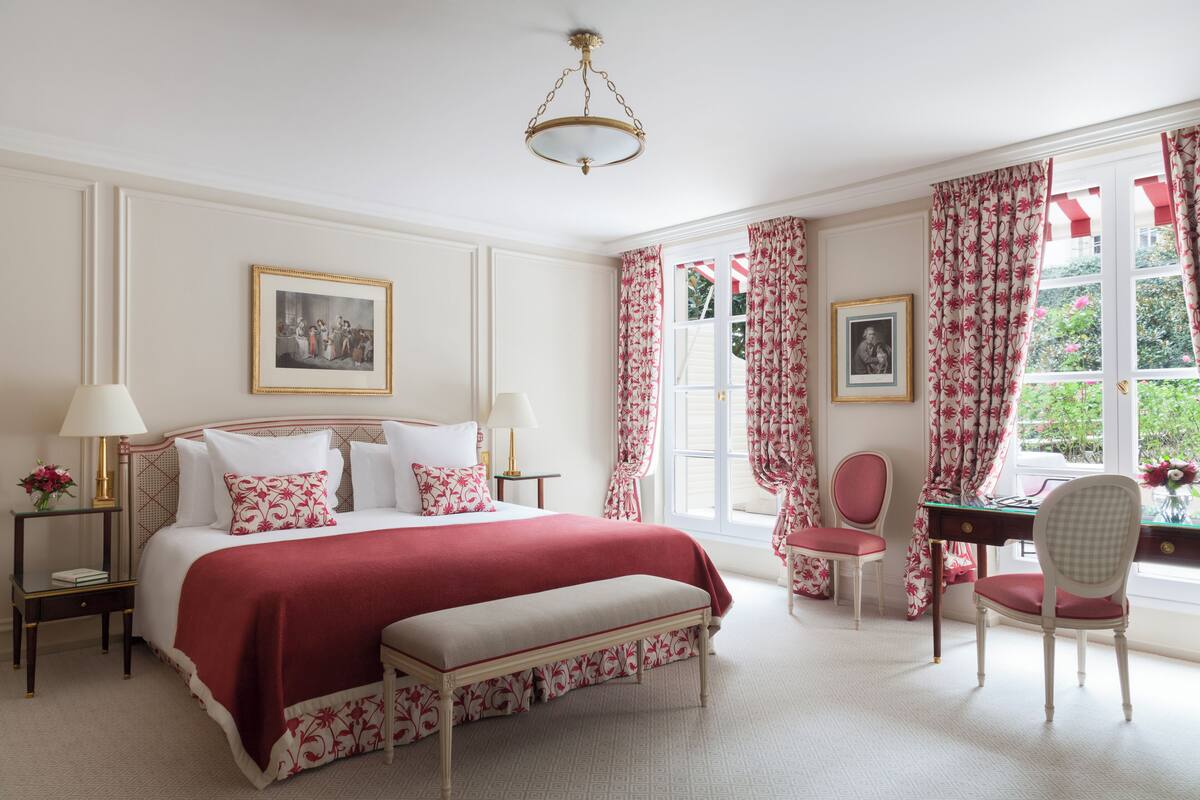 A bedroom with a large bed, bedside tables, a desk, and chairs.