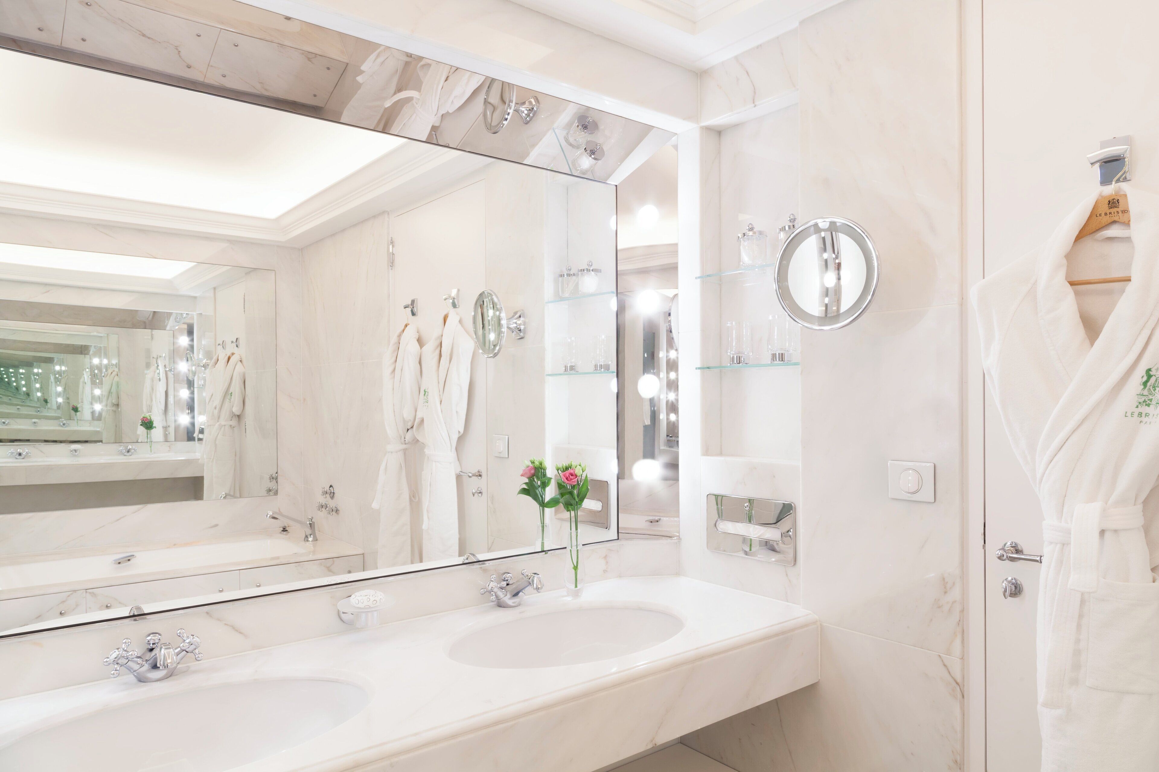 A modern bathroom with two sinks, a large mirror, and a glass shower enclosure.