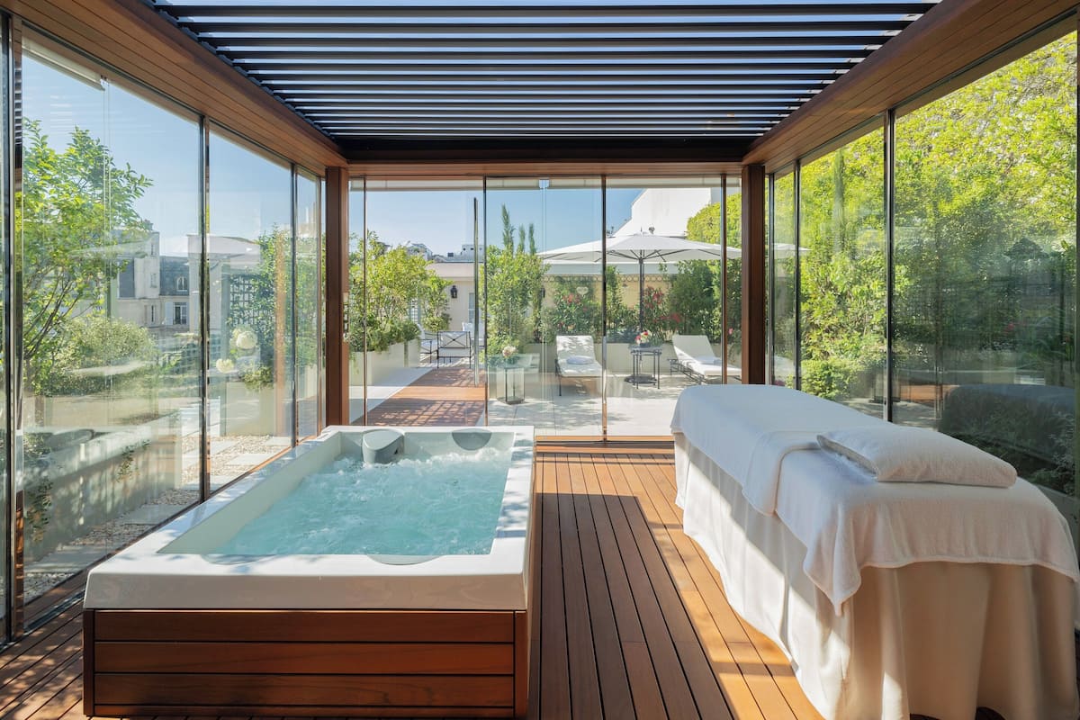 A spa area with a hot tub and a massage table, large glass windows, and a wooden deck.