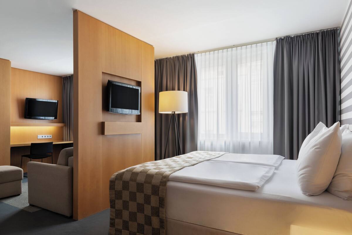 Une chambre d’hôtel comprenant un lit, un bureau avec une chaise, une télévision et une lampe.