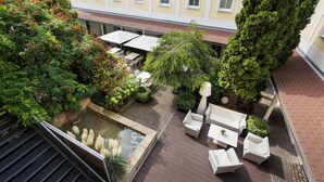 A rooftop garden with a small pond, outdoor seating, and a view of a yellow building with windows. - Holiday Inn Vienna City by IHG (Vienna)