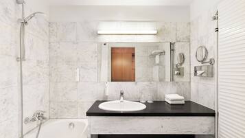 A modern bathroom with a white sink, a mirror, a towel rack, and a shower.
