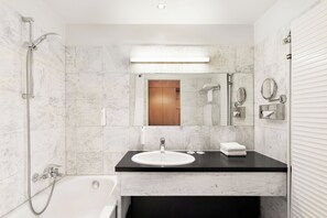 A modern bathroom with a white sink, a mirror, a towel rack, and a shower.