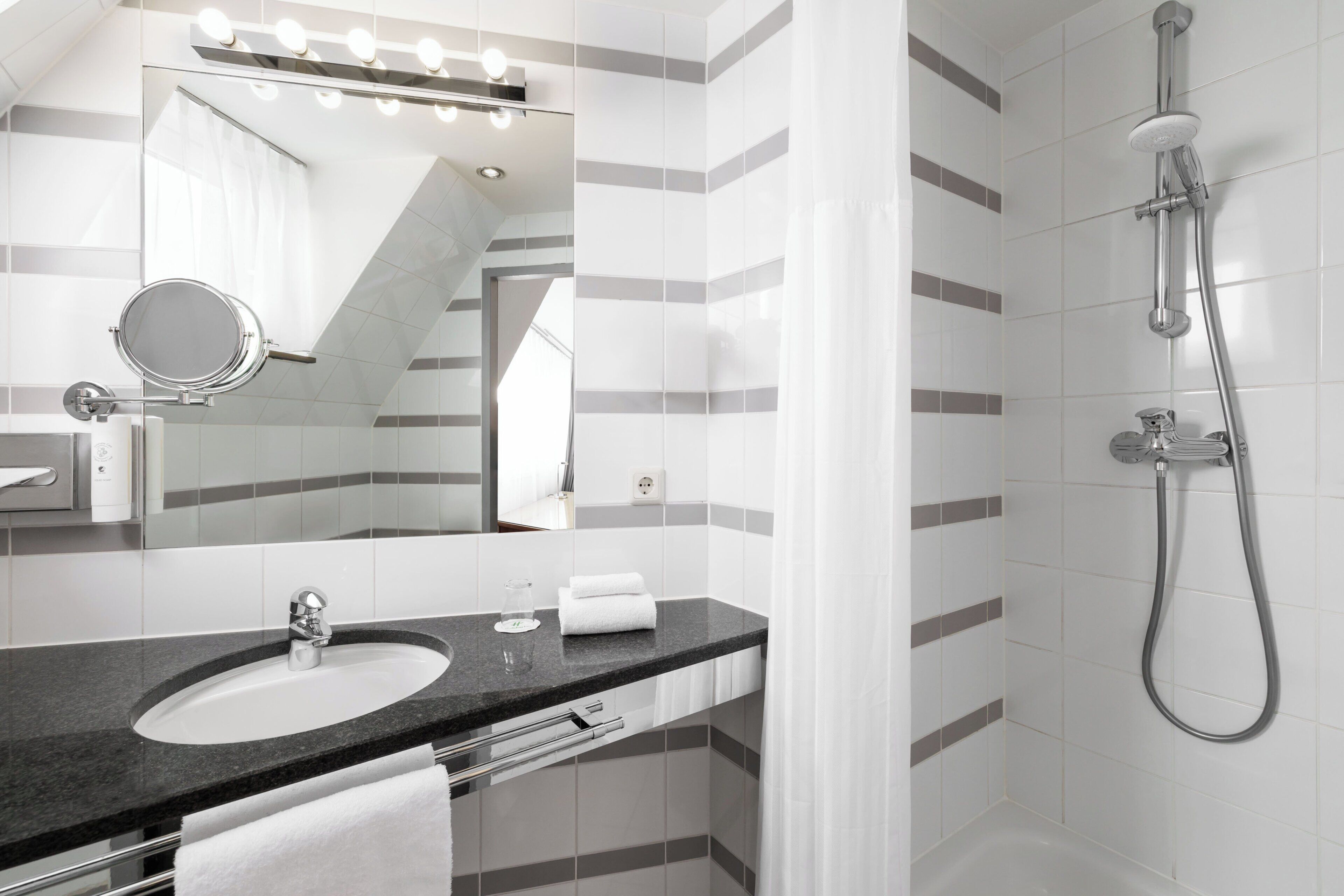 A modern bathroom with a sink, mirror, and shower.