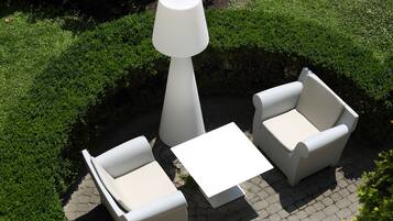 A patio area with two white armchairs, a small white table, and a tall white lamp.