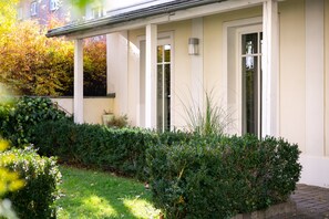 A building with a white exterior, a covered porch, and a well-maintained garden with hedges and a lawn. - Holiday Inn Vienna City by IHG (Vienna)