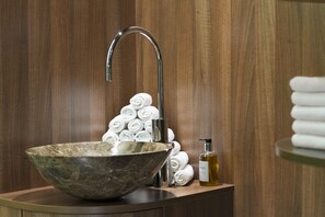 A bathroom with a marble sink, a chrome faucet, and a stack of white towels. - Holiday Inn Vienna City by IHG (Vienna)