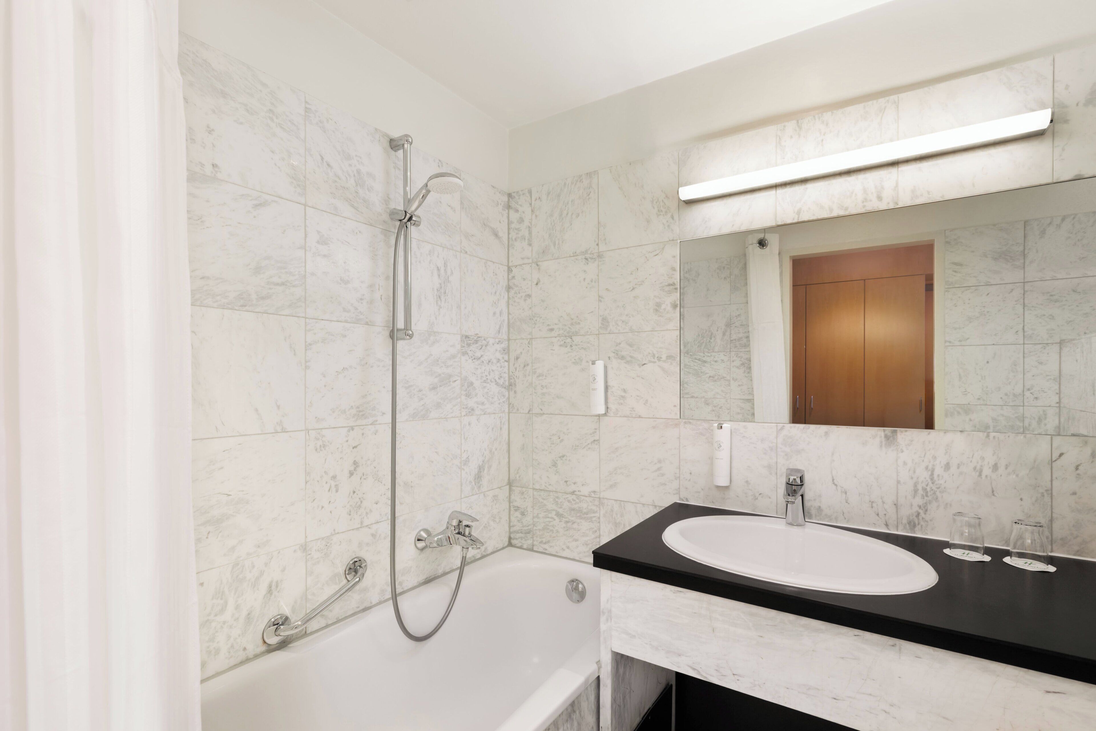 A bathroom with a bathtub, a sink, a mirror, and a shower.
