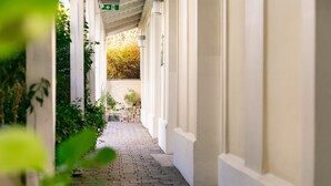 A covered walkway with brick flooring, white walls, and green plants. - Holiday Inn Vienna City by IHG (Vienna)
