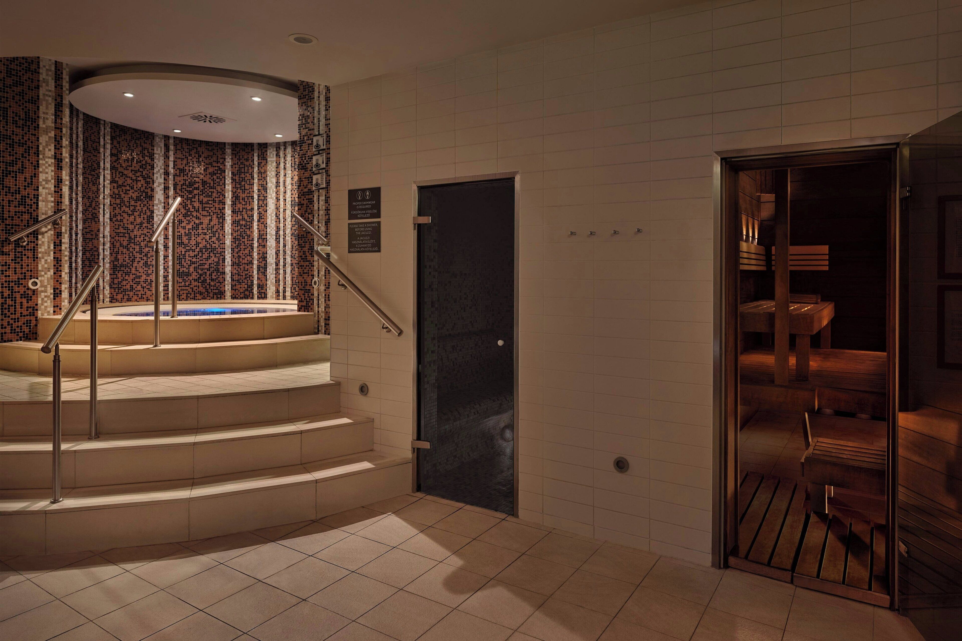A modern hotel lobby with a spiral staircase, a reception area, and a view of the interior through a glass door.