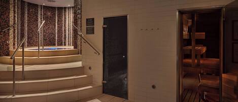 A modern hotel lobby with a spiral staircase, a reception area, and a view of the interior through a glass door.