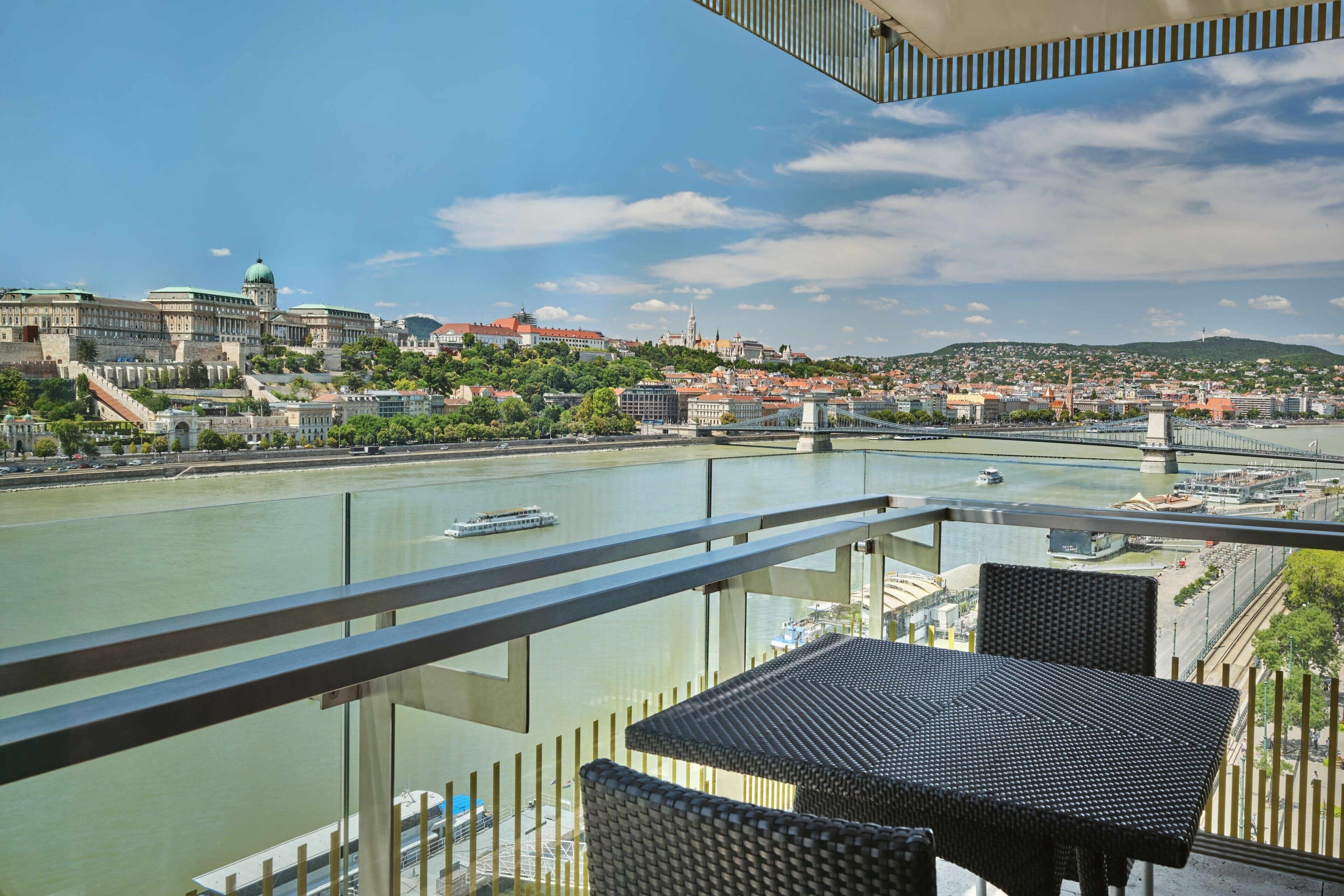 A balcony with a view of a river, cityscape, and a bridge.