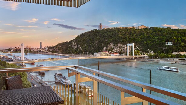 Un balcon avec vue sur un pont, une rivière et des bateaux.