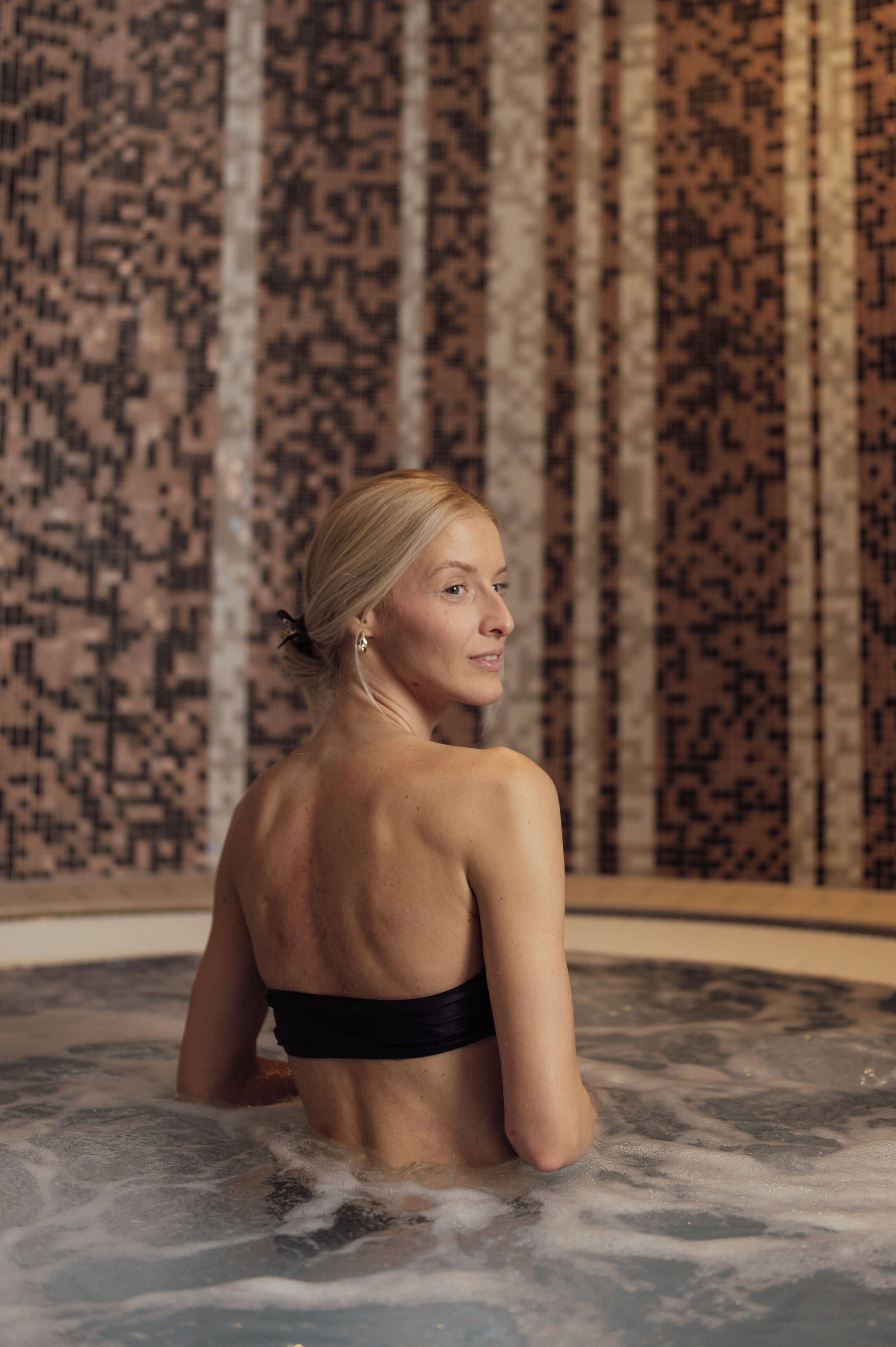 Una persona en un jacuzzi con una pared estampada al fondo.