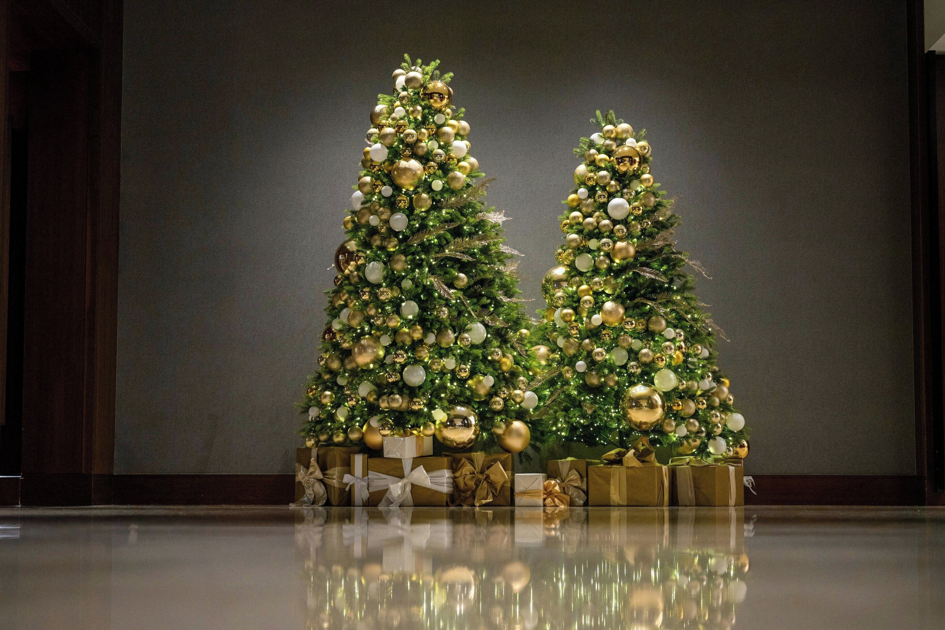 Two Christmas trees with ornaments and presents underneath.