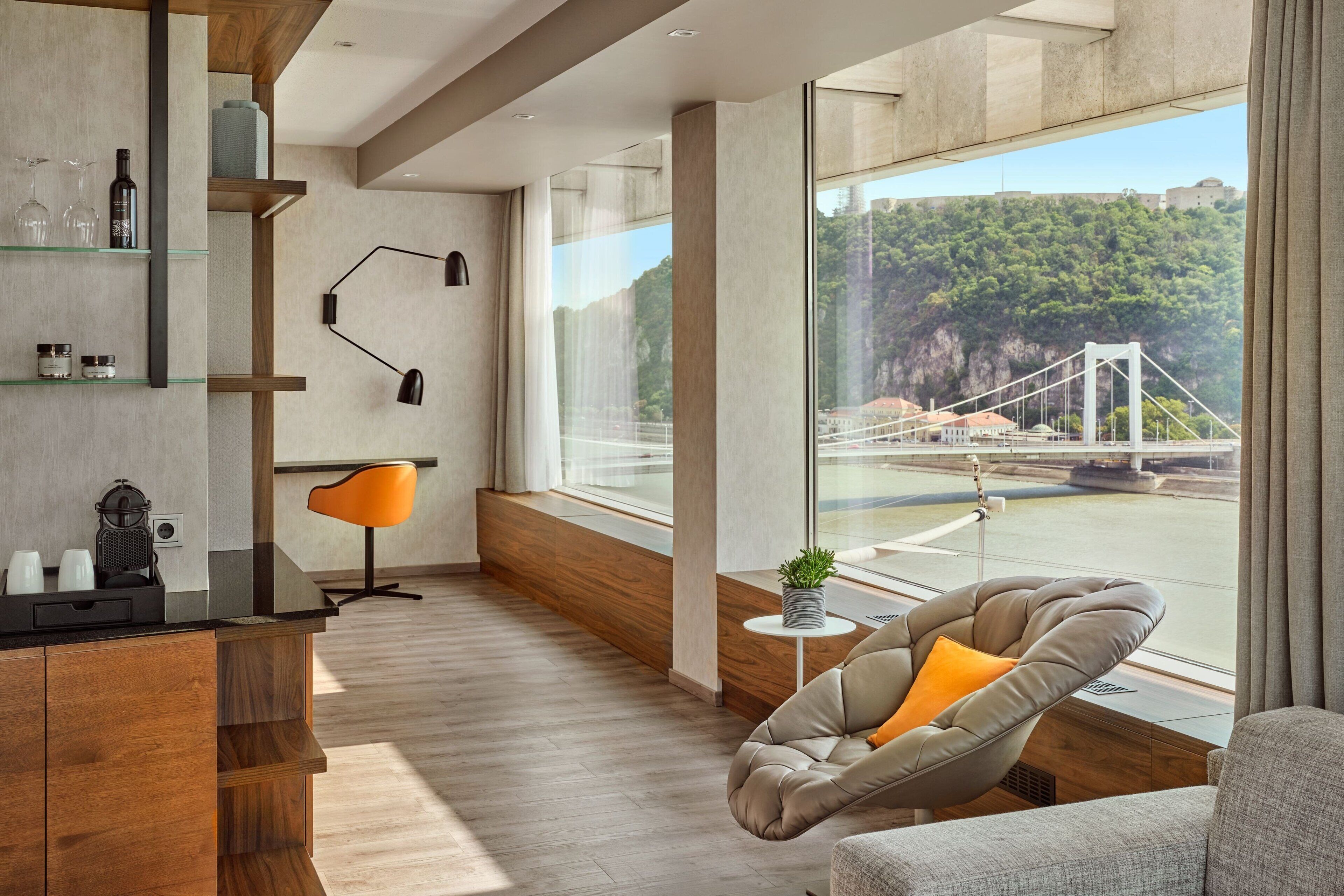 A modern living room with a large window, a sofa, a chair, and a wooden cabinet.