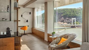 A modern living room with a large window, a sofa, a chair, and a wooden cabinet.