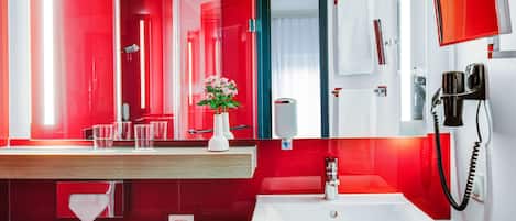 Un baño moderno con una decoración en rojo y blanco, un espejo grande, un lavabo, un perchero para toallas y un teléfono montado.