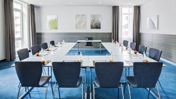 Een vergaderruimte met een lange tafel, stoelen en kunstwerken aan de wanden.