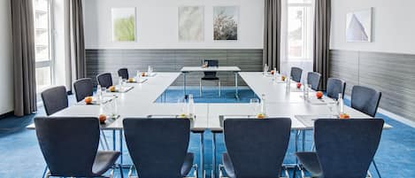 A conference room with a long table, chairs, and artwork on the walls.