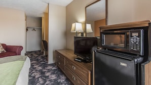 A hotel room with a bed, a TV, a refrigerator, a microwave, a lamp, and a mirror. - Rodeway Inn Jackson Northwest (Jackson)