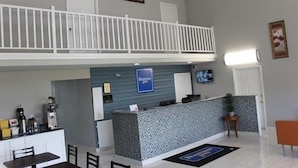 A hotel reception area with a reception desk, a coffee machine, a seating area, and a balcony. - Rodeway Inn Jackson Northwest (Jackson)
