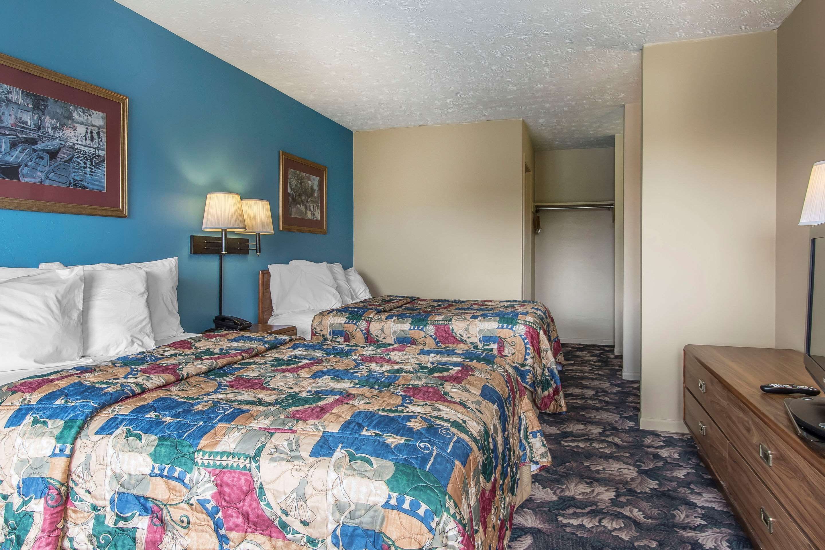 Une chambre d’hôtel avec un lit, une commode, une lampe et un placard.
