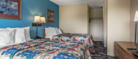 Une chambre d’hôtel avec un lit, une commode, une lampe et un placard.