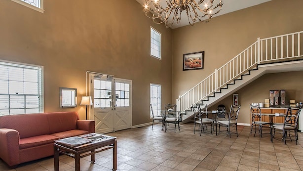 A spacious living area with a sofa, coffee table, and dining setup. A staircase leads to an upper level. - Rodeway Inn Jackson Northwest (Jackson)