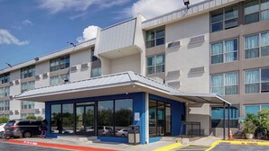 A modern hotel with a covered entrance, large windows, and a parking area marked with 'No Parking' signs. - Motel 6 Fort Worth, TX - Downtown East (Fort Worth)