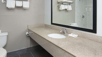 A bathroom with a white sink, a mirror, and a towel rack with multiple towels.
