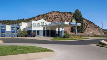 Un Days Inn con un diseño moderno, una estación de servicio y un paisaje montañoso al fondo.